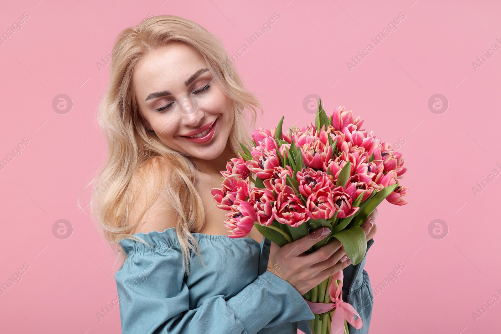 Photo of Happy young woman with beautiful bouquet on dusty pink background