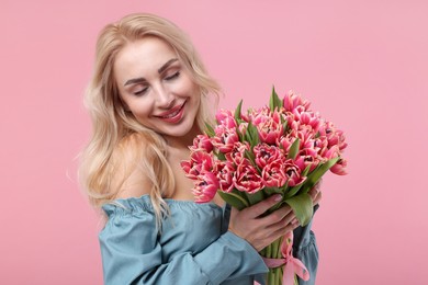 Happy young woman with beautiful bouquet on dusty pink background