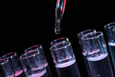 Photo of Dripping reagent into test tube on black background, closeup. Laboratory analysis