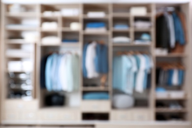 Photo of Blurred view of large wardrobe closet with clothes and home stuff