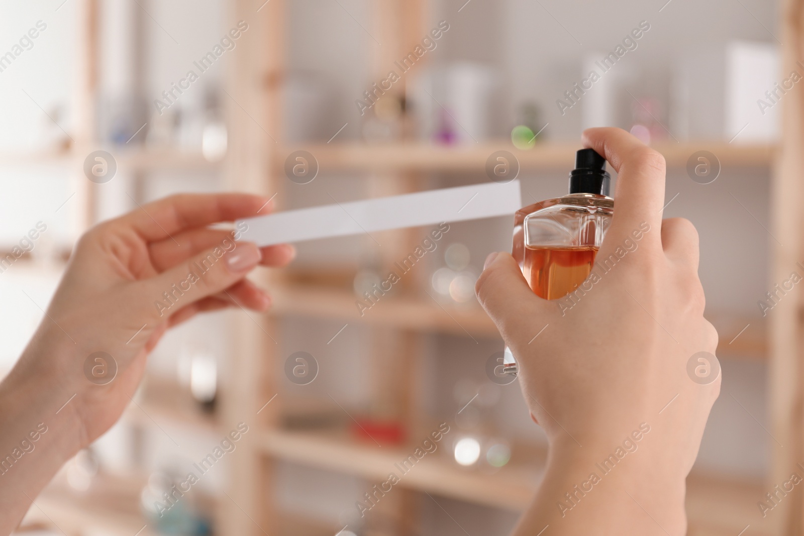 Photo of Woman with bottle of perfume and blotter indoors, closeup