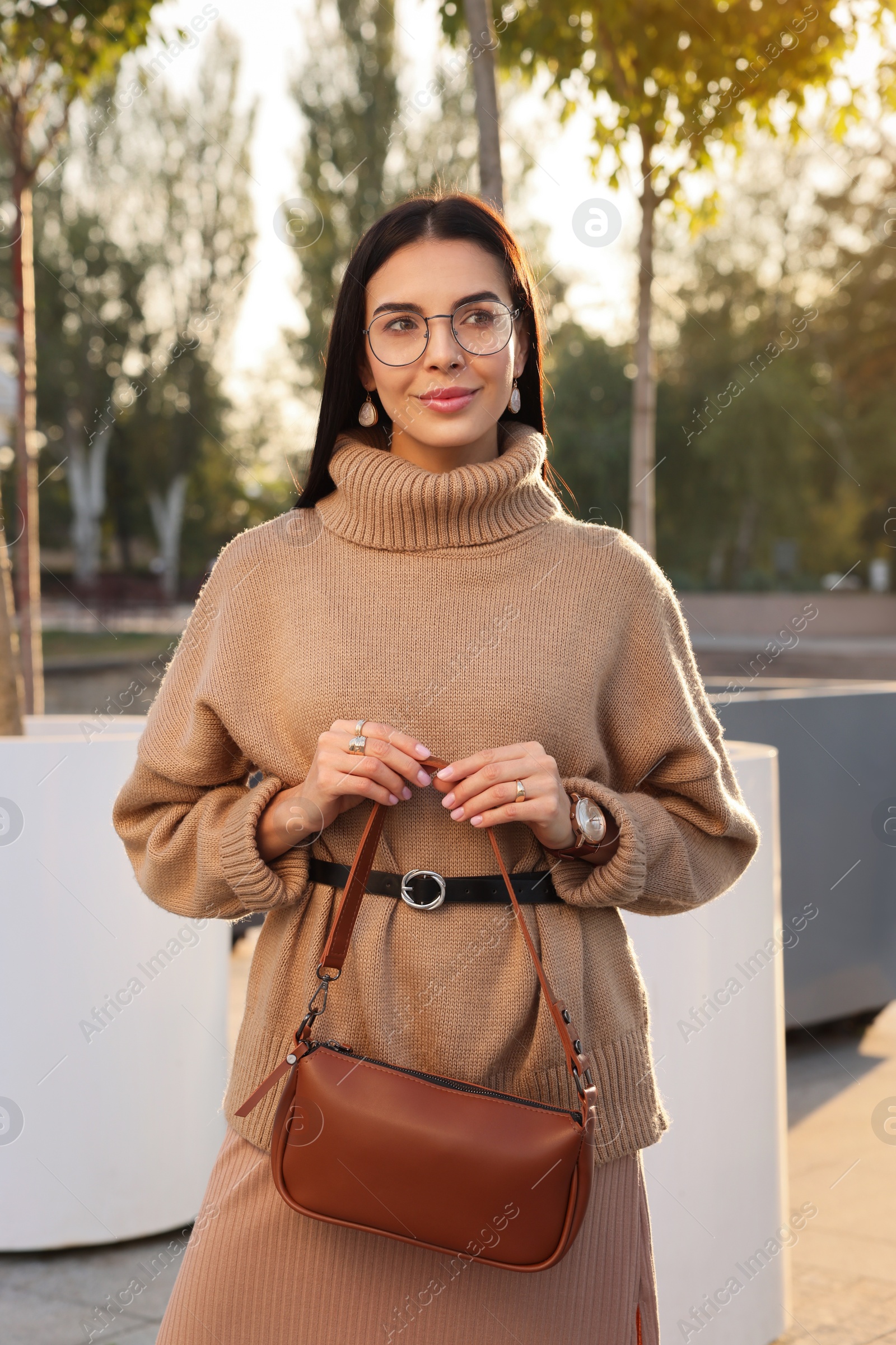 Photo of Fashionable young woman with stylish bag on city street