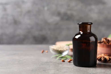 Photo of Bottle of anise essential oil on grey table. Space for text