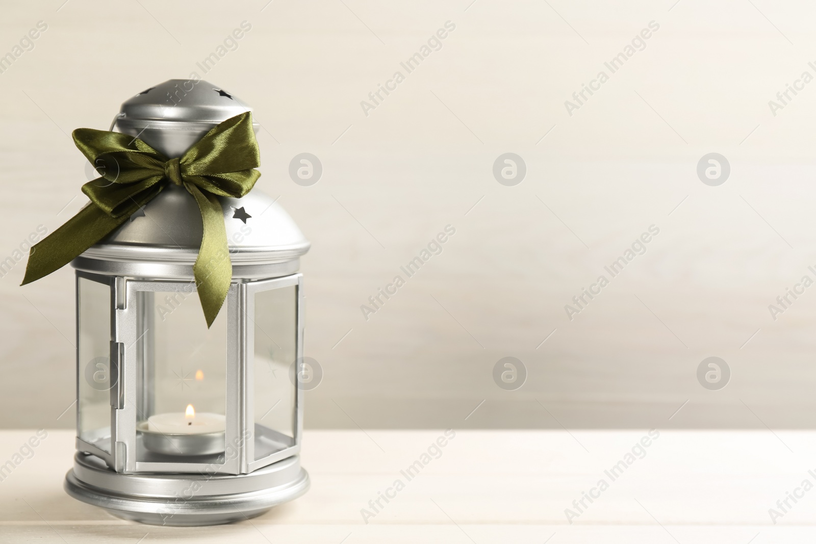 Photo of Beautiful decorative Christmas lantern with burning candle on white wooden table. Space for text