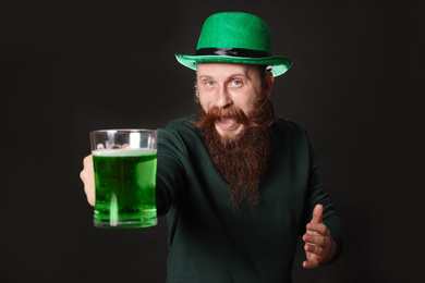 Photo of Bearded man with green beer on black background. St. Patrick's Day celebration