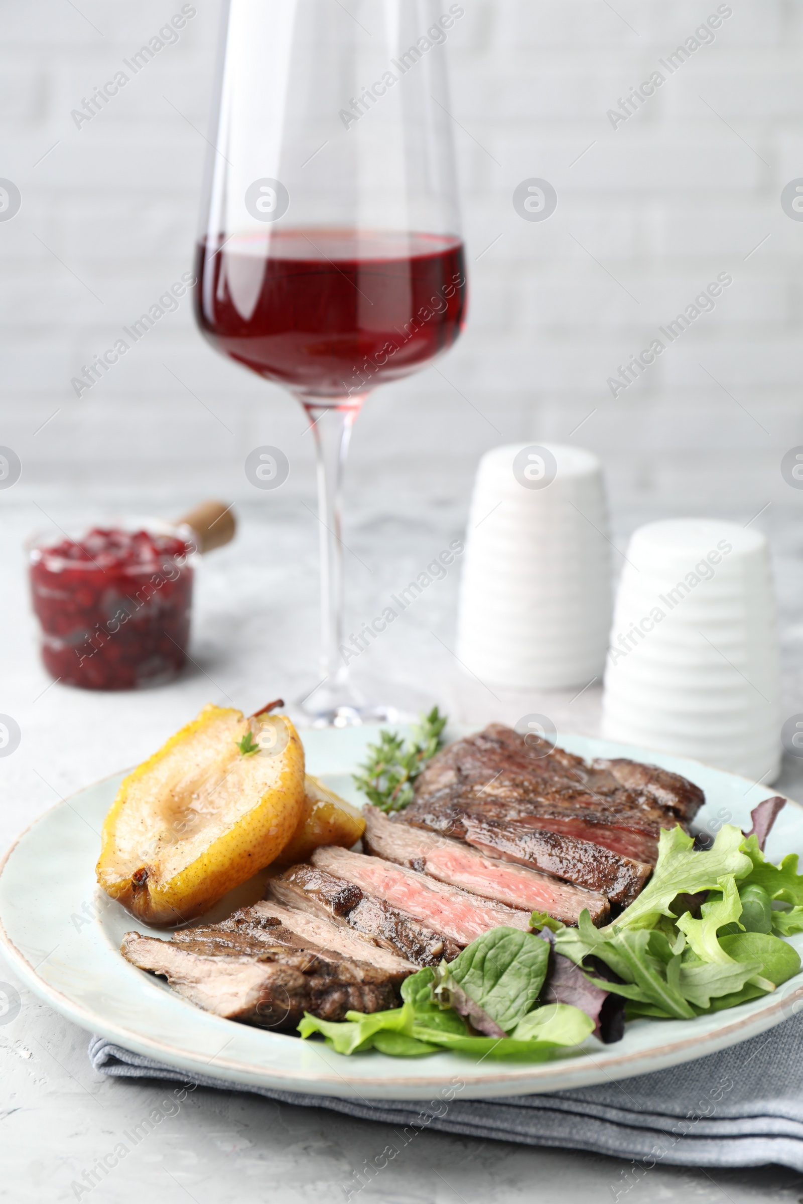 Photo of Delicious roasted beef meat, caramelized pear and greens served on table, closeup