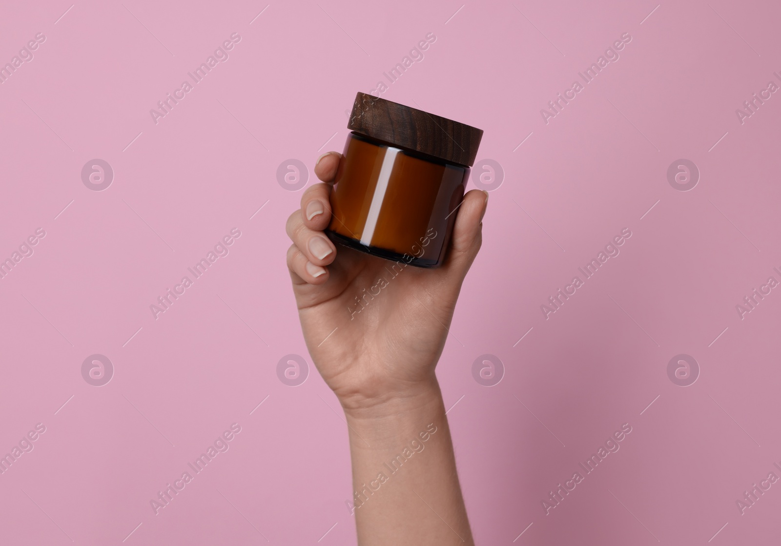 Photo of Woman holding jar of cosmetic product on pink background, closeup