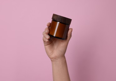 Photo of Woman holding jar of cosmetic product on pink background, closeup