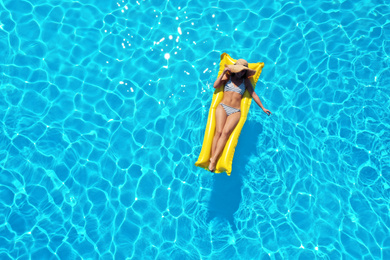 Image of Young woman with inflatable mattress in swimming pool, top view