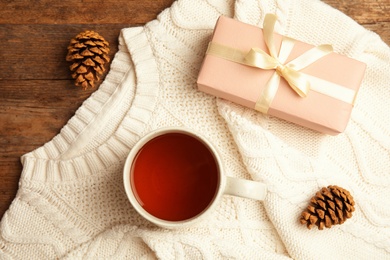 Photo of Flat lay composition with cup of hot winter drink and warm knitted sweater on wooden background. Cozy season