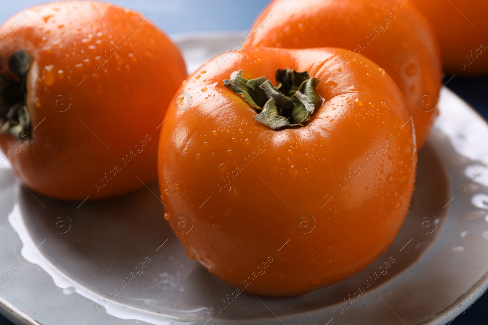 Photo of Delicious ripe persimmons on plate, closeup view