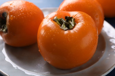 Delicious ripe persimmons on plate, closeup view