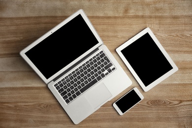 Photo of Devices with blank screens on wooden background, top view. Mock up for design