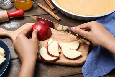Photo of Woman cutting apple at wooden table, closeup. Baking pie