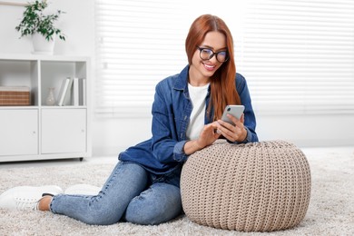 Happy young woman having video chat via smartphone at home