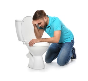 Photo of Young man suffering from nausea near toilet bowl isolated on white