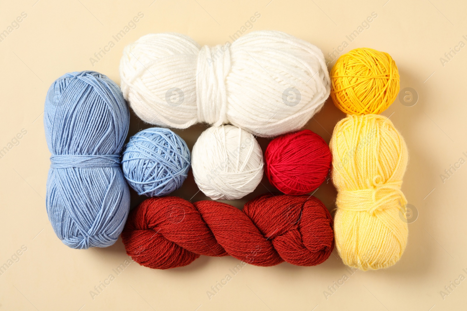 Photo of Colorful woolen yarns on beige background, flat lay