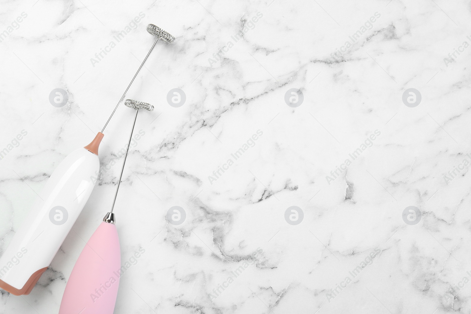 Photo of Pink milk frother wands on white marble table, top view. Space for text