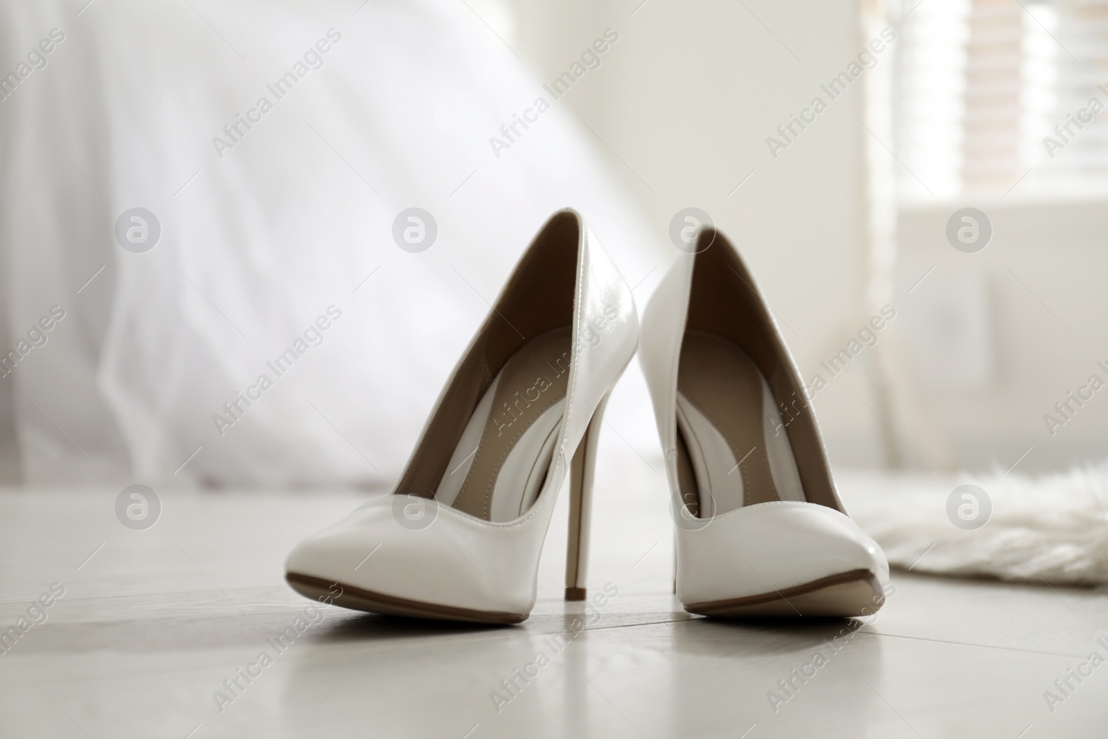 Photo of White wedding shoes on floor in room