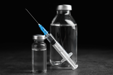 Photo of Vials and syringe on grey table. Vaccination and immunization