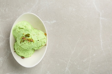 Photo of Tasty pistachio ice cream on light table, top view. Space for text