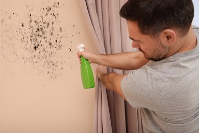 Image of Man in using mold remover on wall in room