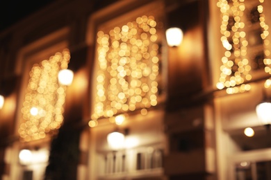 Blurred view of building with beautiful street lights at night. Bokeh effect