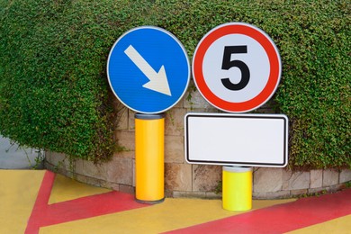 Photo of Different road signs near green bush outdoors