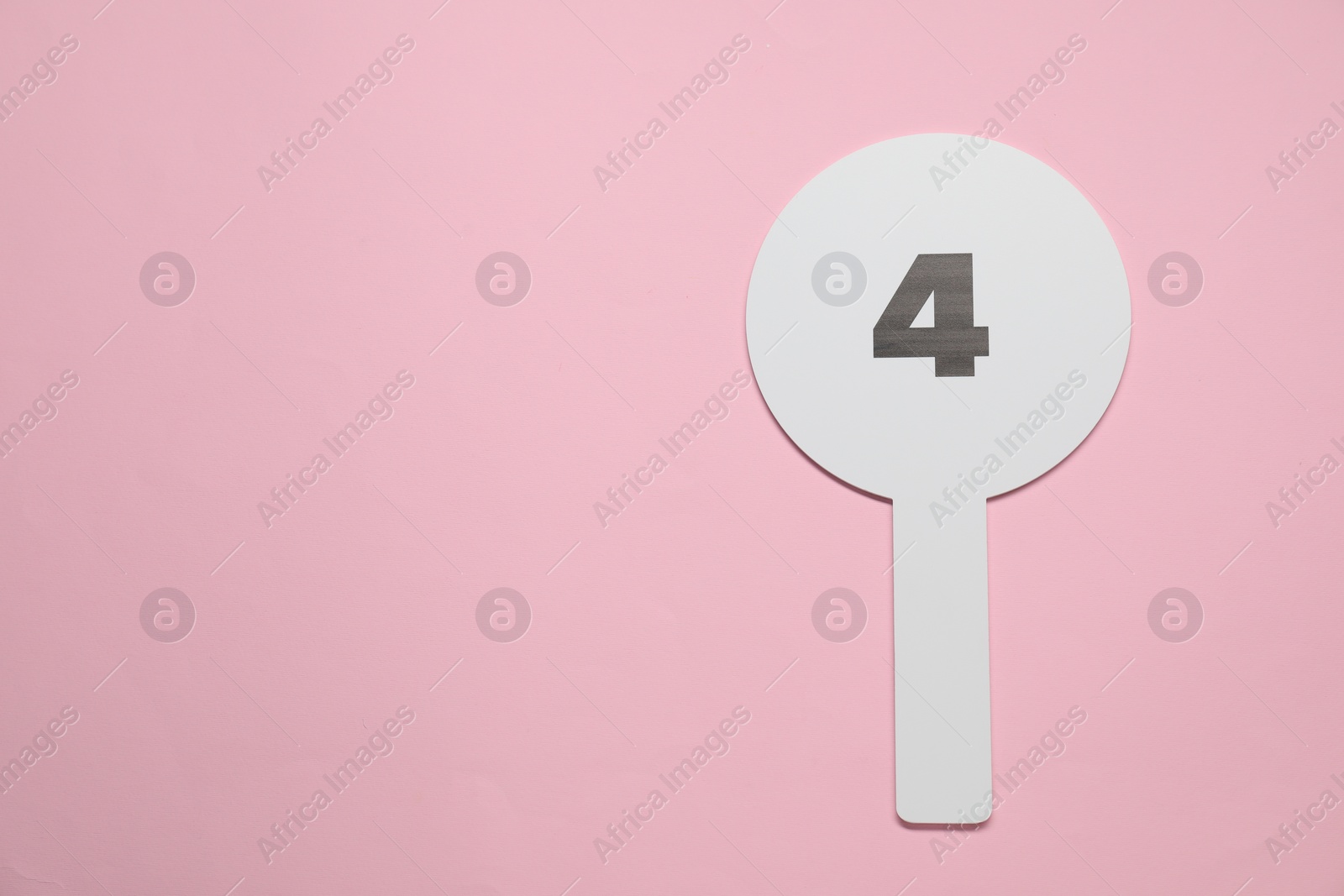 Photo of Auction paddle with number 4 on pink background, top view. Space for text