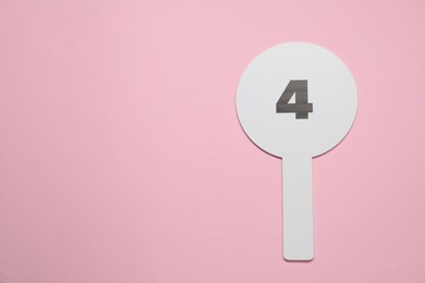 Auction paddle with number 4 on pink background, top view. Space for text