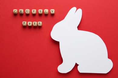 Photo of Wooden cubes with text Cruelty Free and figure of rabbit on red background, flat lay. Stop animal tests