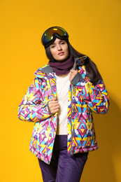 Photo of Woman wearing stylish winter sport clothes on yellow background