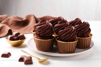 Photo of Delicious cupcake and chocolate pieces on white wooden table