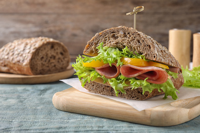 Photo of Tasty sandwich with ham on light blue wooden table, closeup