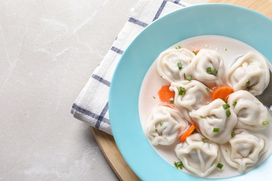 Photo of Board with plate of dumplings on grey marble table, top view. Space for text