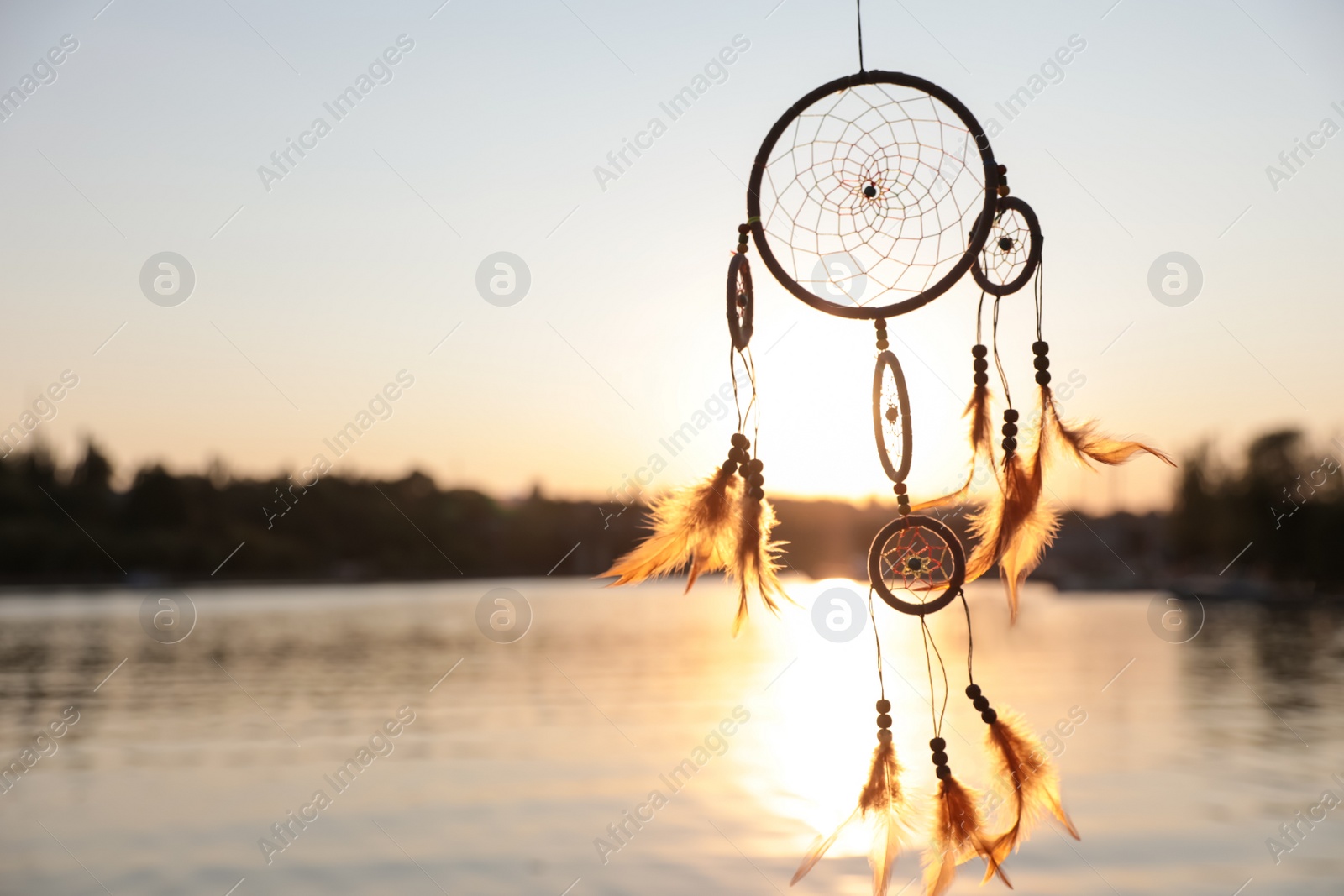 Photo of Beautiful handmade dream catcher near river on sunny day. Space for text