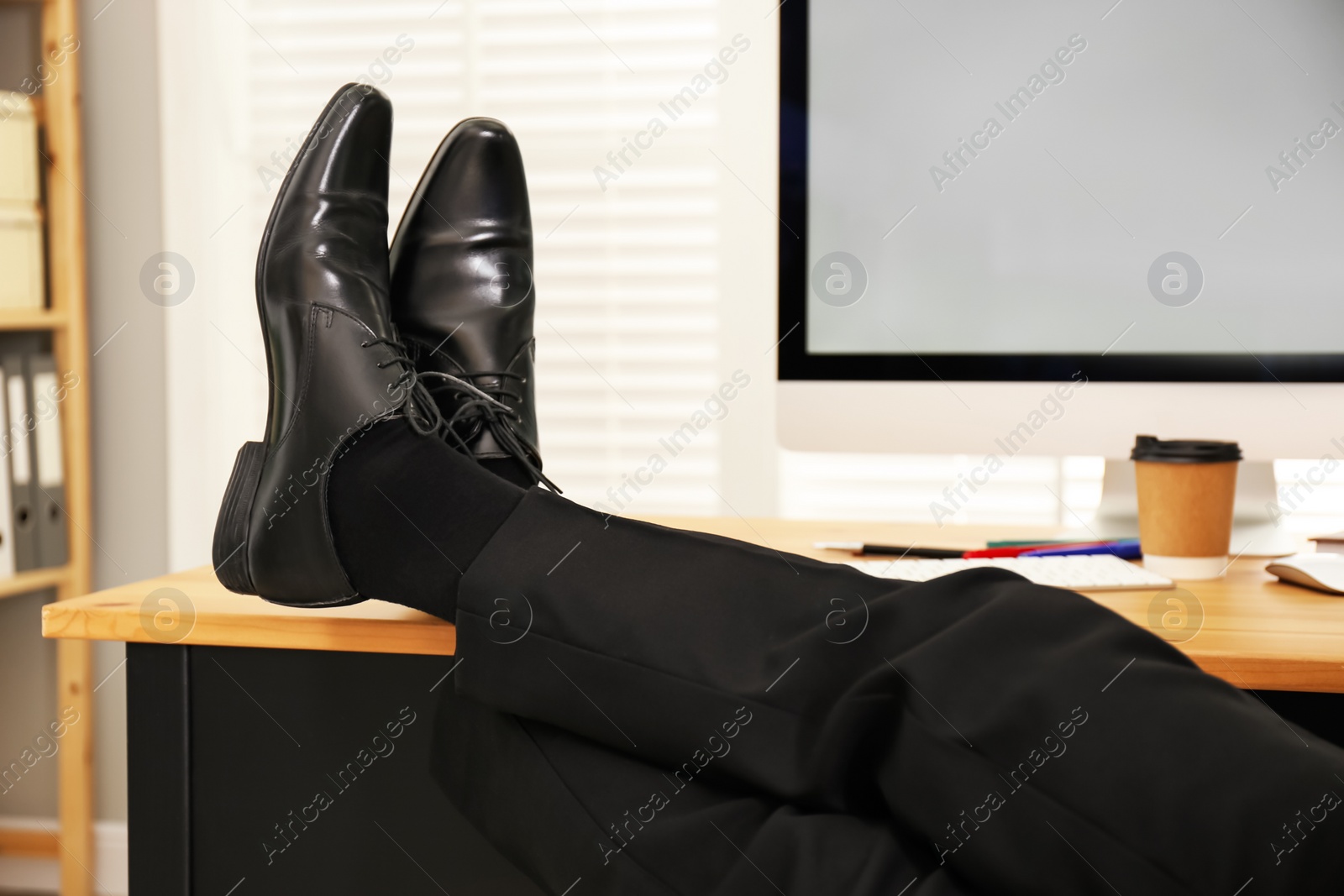 Photo of Lazy employee resting at table in office, closeup of legs