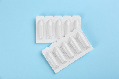 Photo of Suppositories on light blue background, flat lay. Hemorrhoid treatment