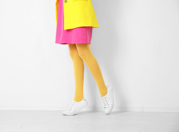 Photo of Woman wearing yellow tights near white wall, closeup