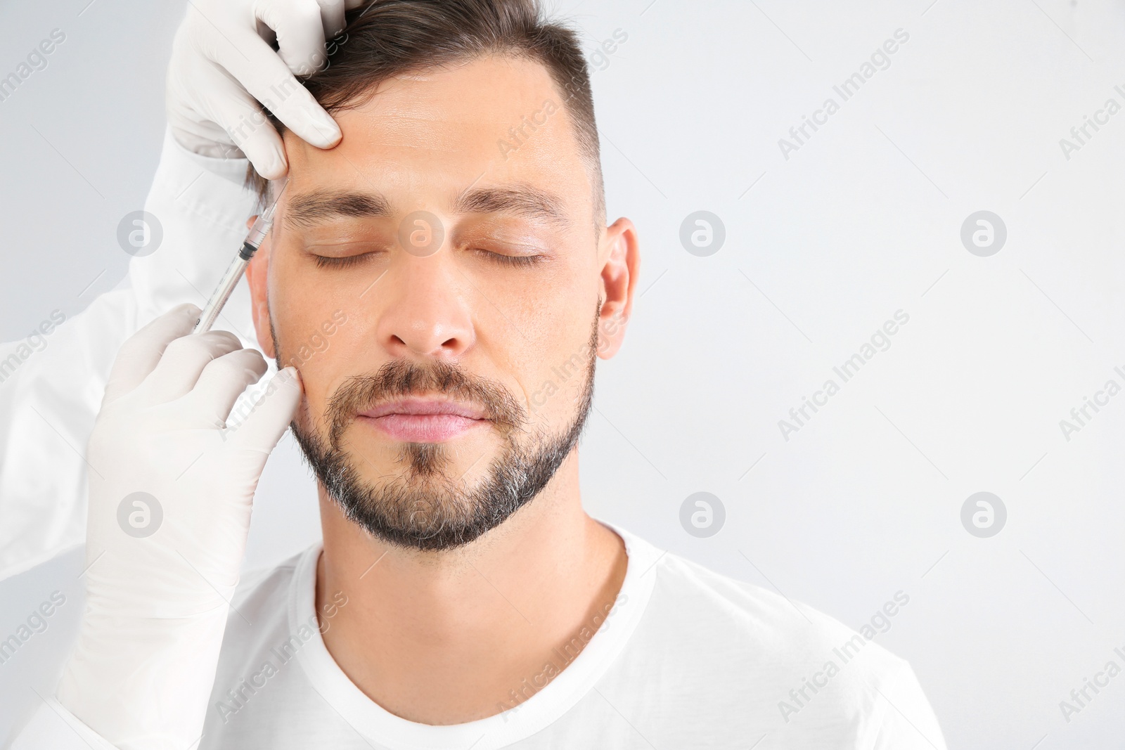 Photo of Mature man getting facial injection on white background. Cosmetic surgery concept