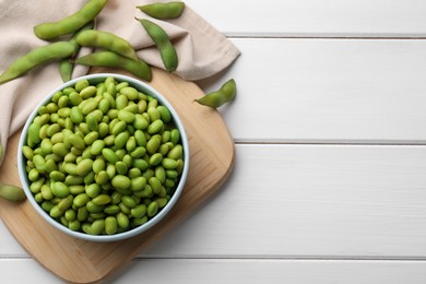 Photo of Organic edamame beans on white wooden table, flat lay. Space for text