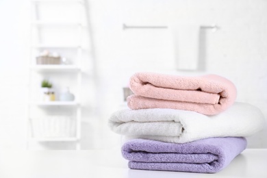 Photo of Stack of fresh towels on table in bathroom. Space for text