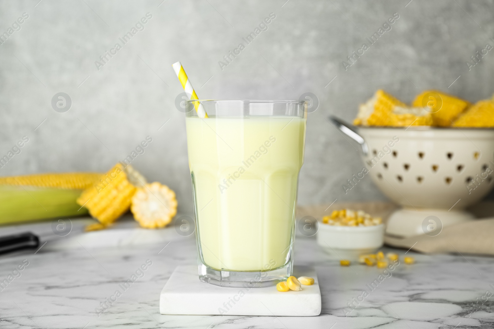 Photo of Tasty fresh corn milk in glass on white marble table