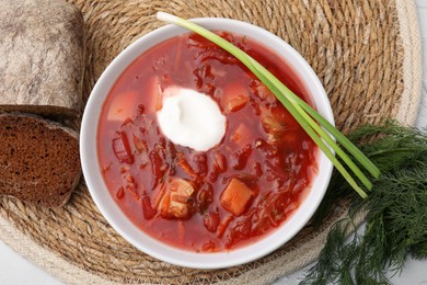 Photo of Tasty borscht with sour cream served on white table, flat lay