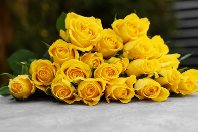 Photo of Beautiful bouquet of yellow roses on light table outdoors