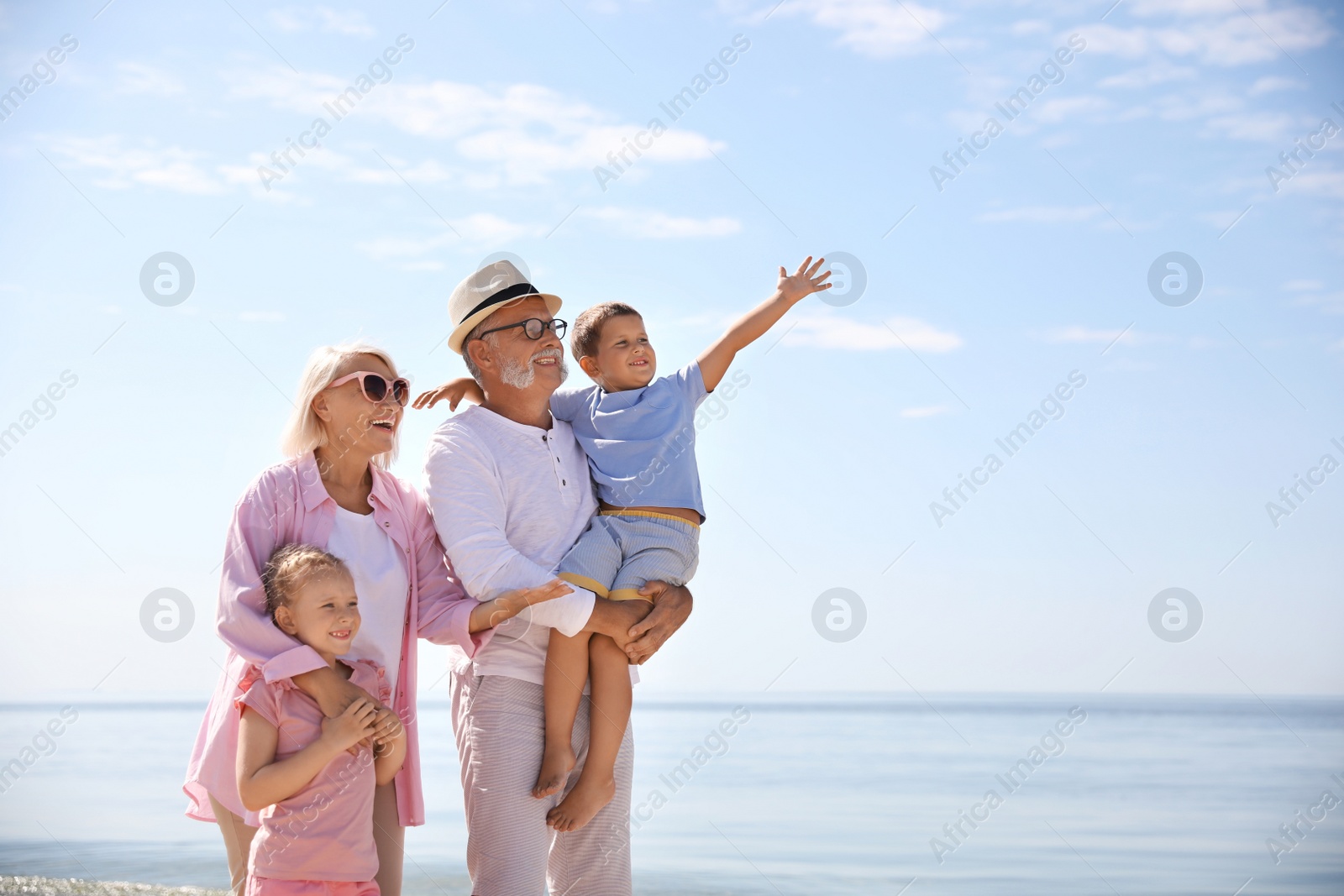 Photo of Happy grandparents with little children on sea beach