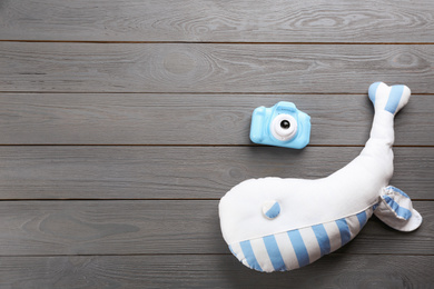 Little photographer's toy camera and stuffed whale on grey wooden background, flat lay. Space for text