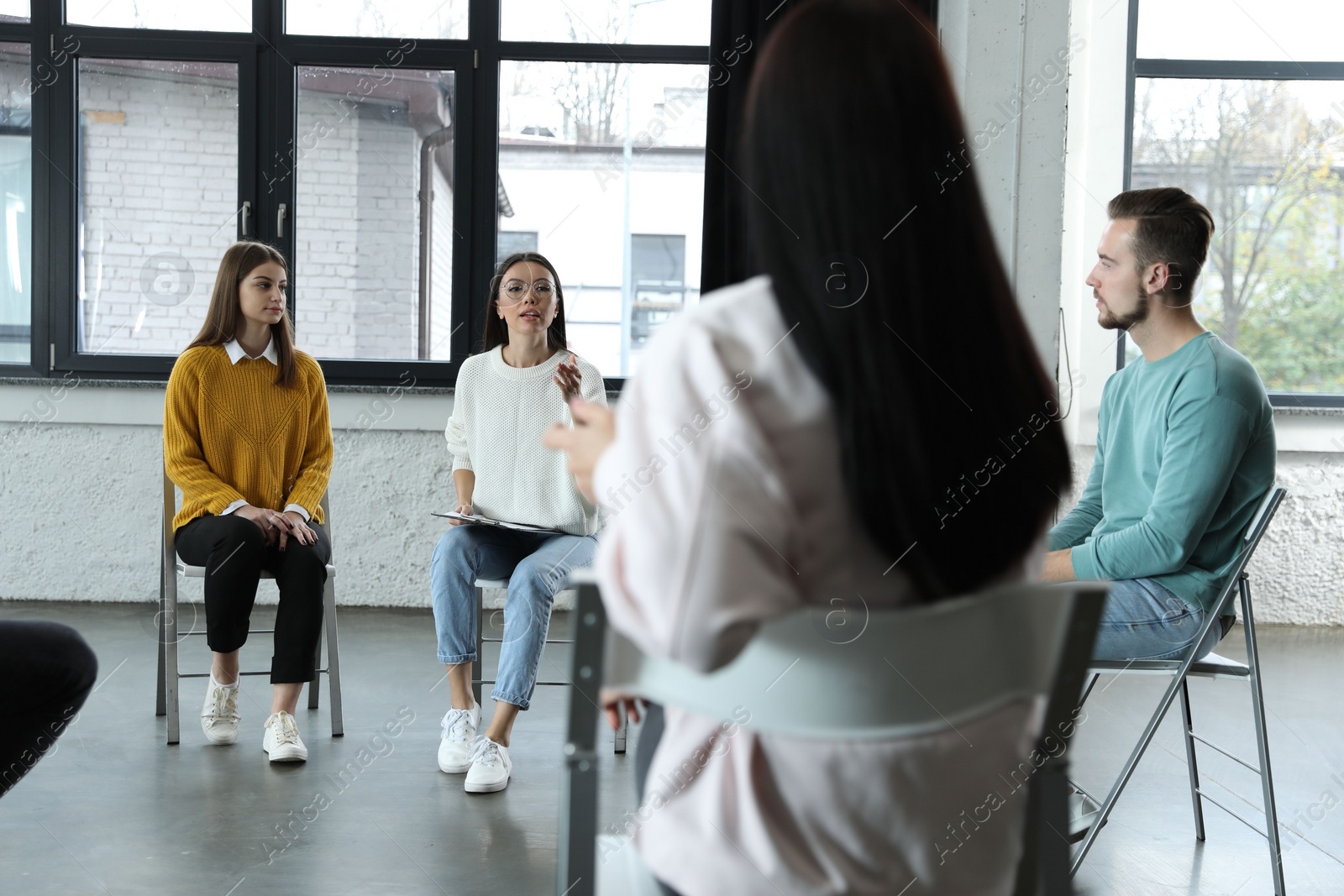 Photo of Psychotherapist working with patients in group therapy session indoors