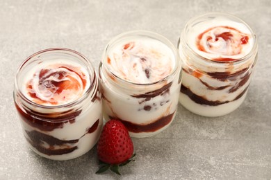 Photo of Tasty yoghurt with jam and strawberry on grey table, closeup