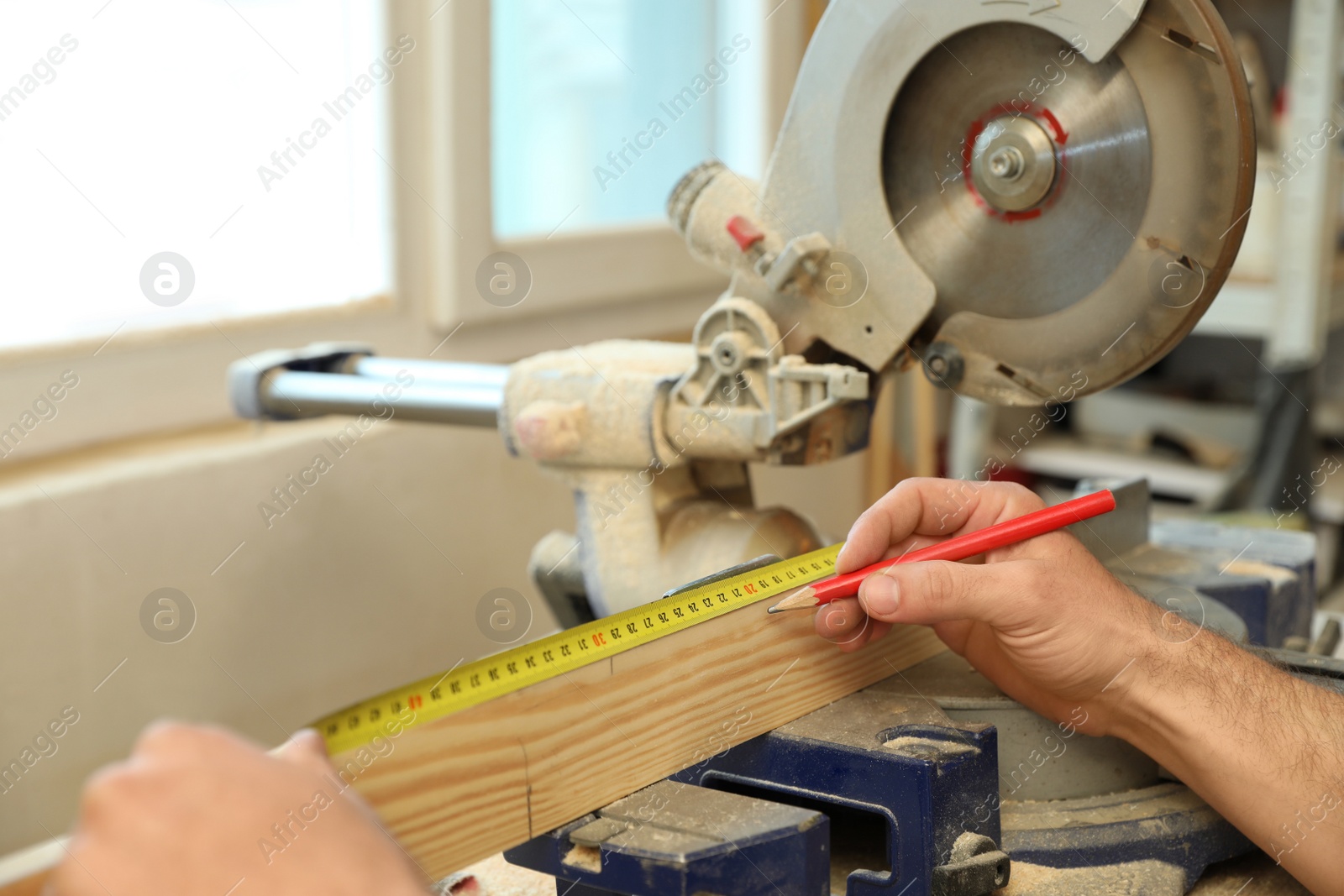 Photo of Working man measuring timber strip in carpentry shop, closeup